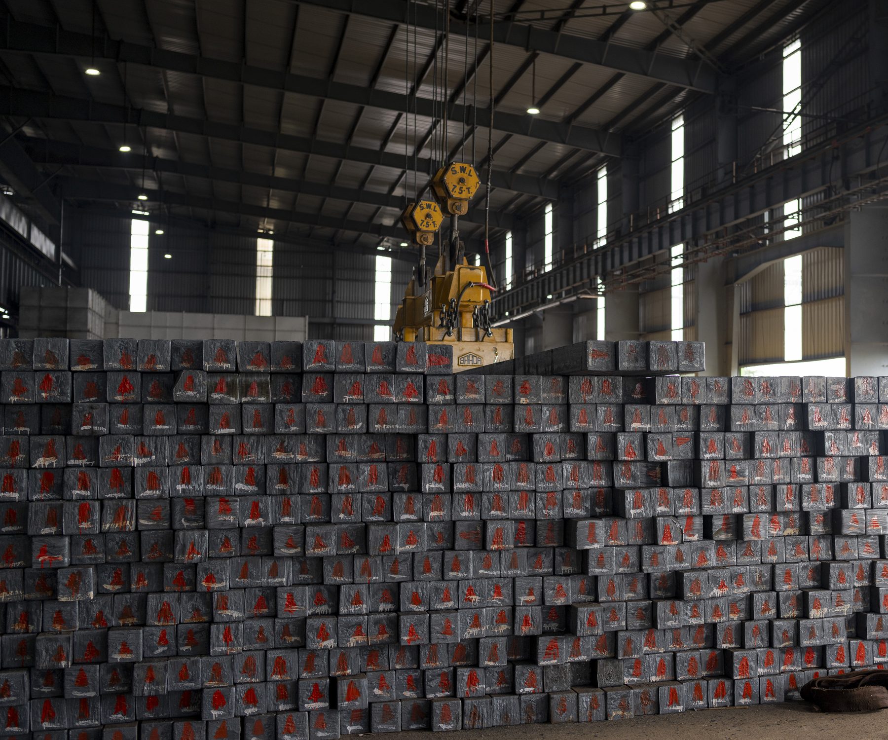 Rows of bundled material stacked under the crane in the bay